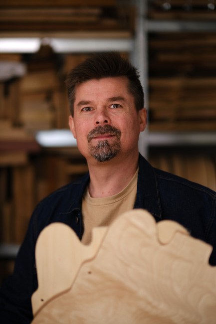 Mikko from Archtop Laminates holding a laminated guitar body component in the workshop